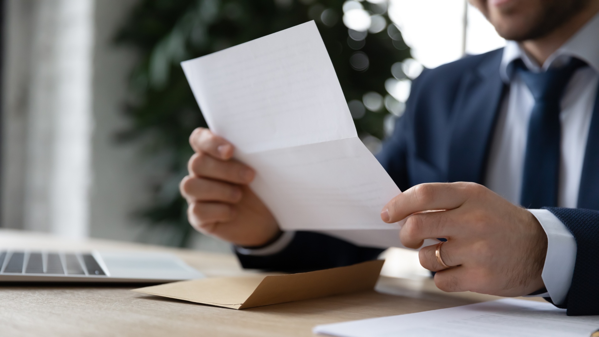 Lecture d'une lettre au bureau Homme en costume lisant une lettre à un bureau